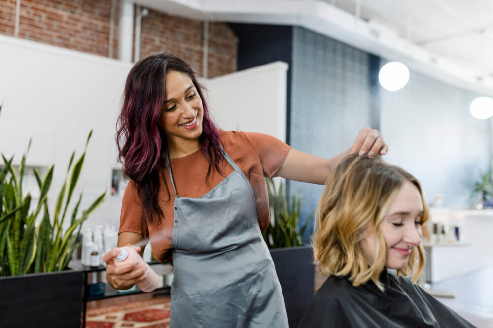 Hairstylist spraying a mouse on her customer's hair Hairstylist spraying a mouse on her customer's hair